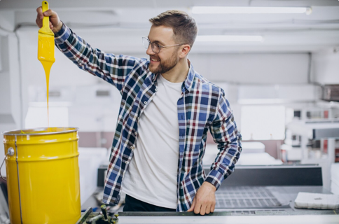 Worker handling yellow ink in workshop